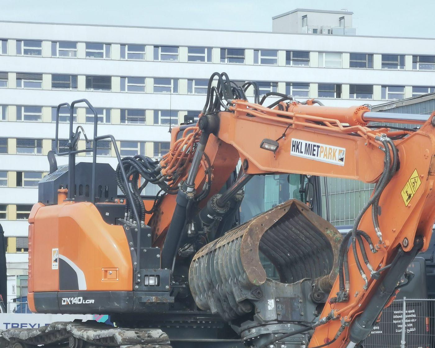 Bagger mit Sortiergreifer vor einem Plattenbau