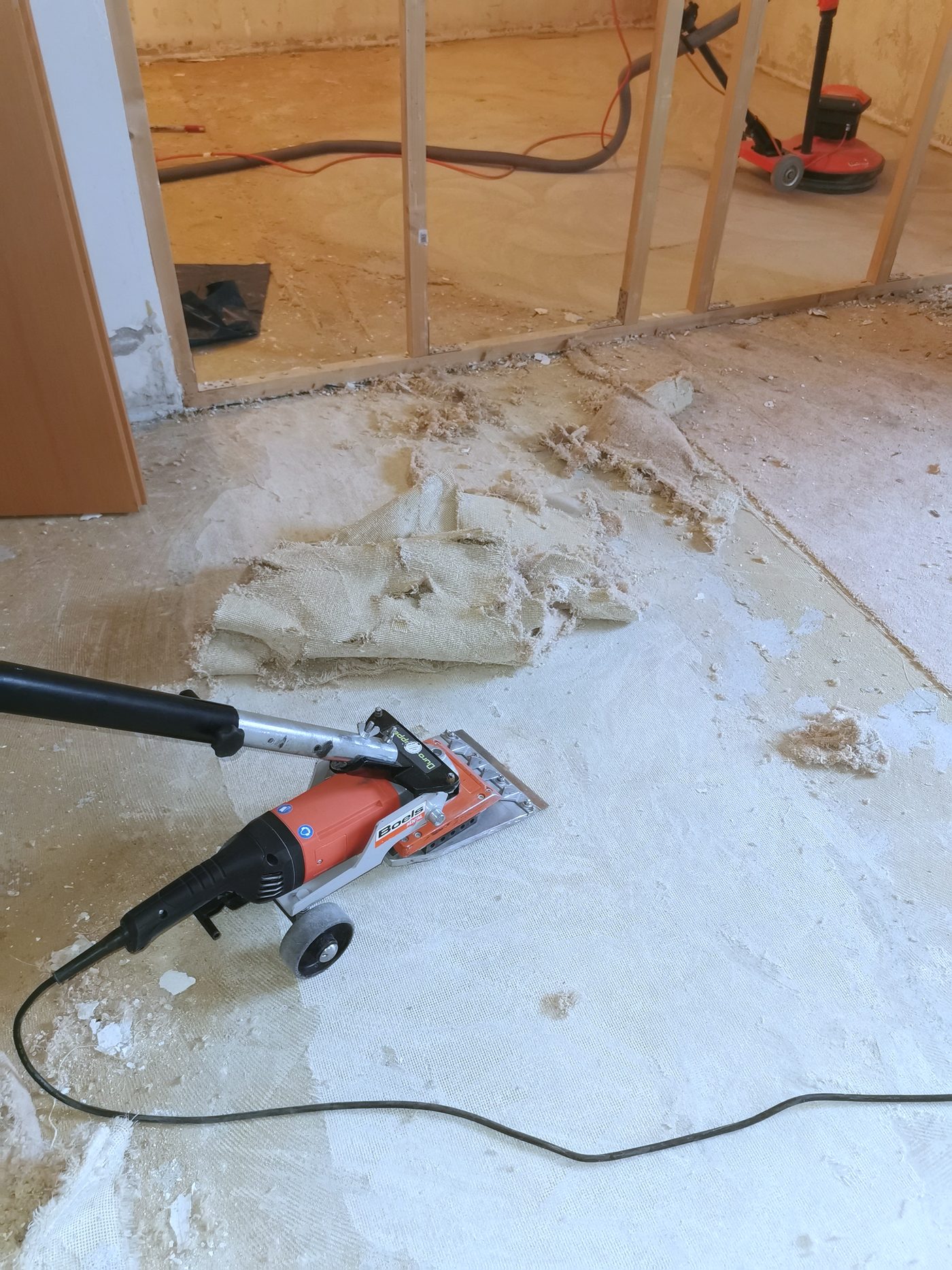 Bodenschleifmaschine nimmt alten Teppichkleber vom Estrich