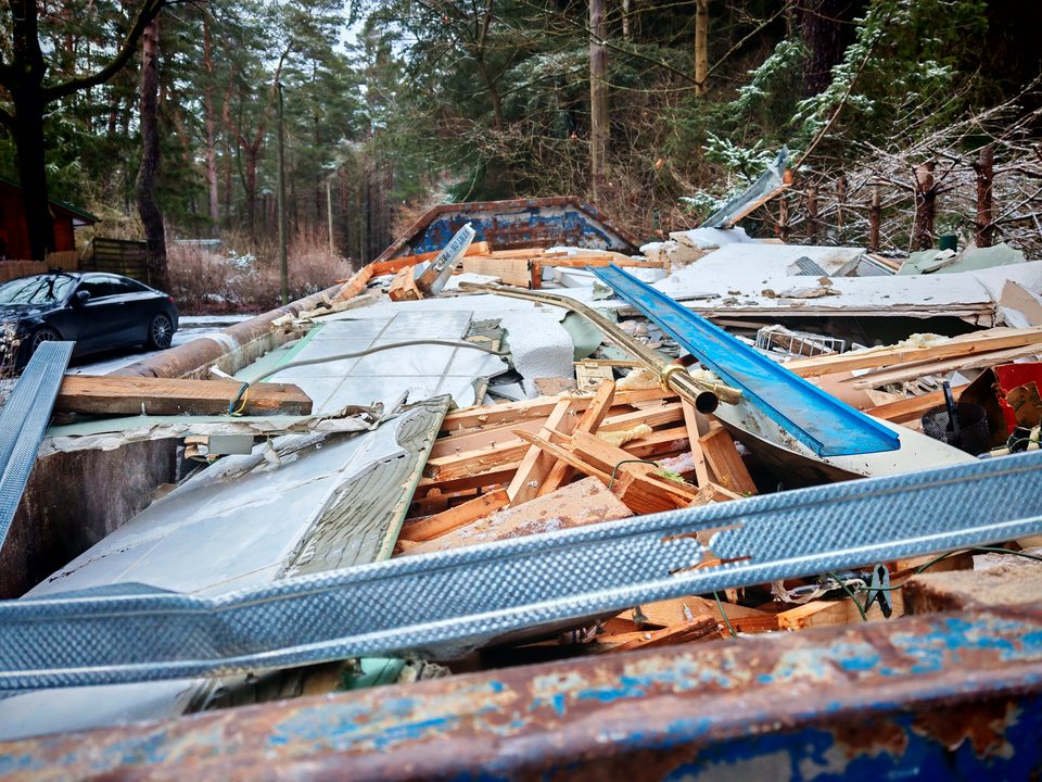 Beladener Bauschuttcontainer im verschneiten Kiefernwald