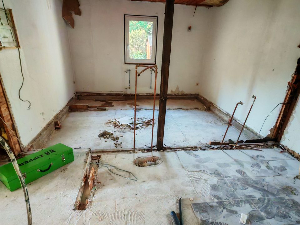 Raum mit altem Fliesenboden, Brechstange liegt bereit, Fliesen teilweise abgenommen