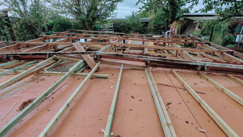 Das abgebaute Dach liegt flach auf dem Boden des Gartenhauses