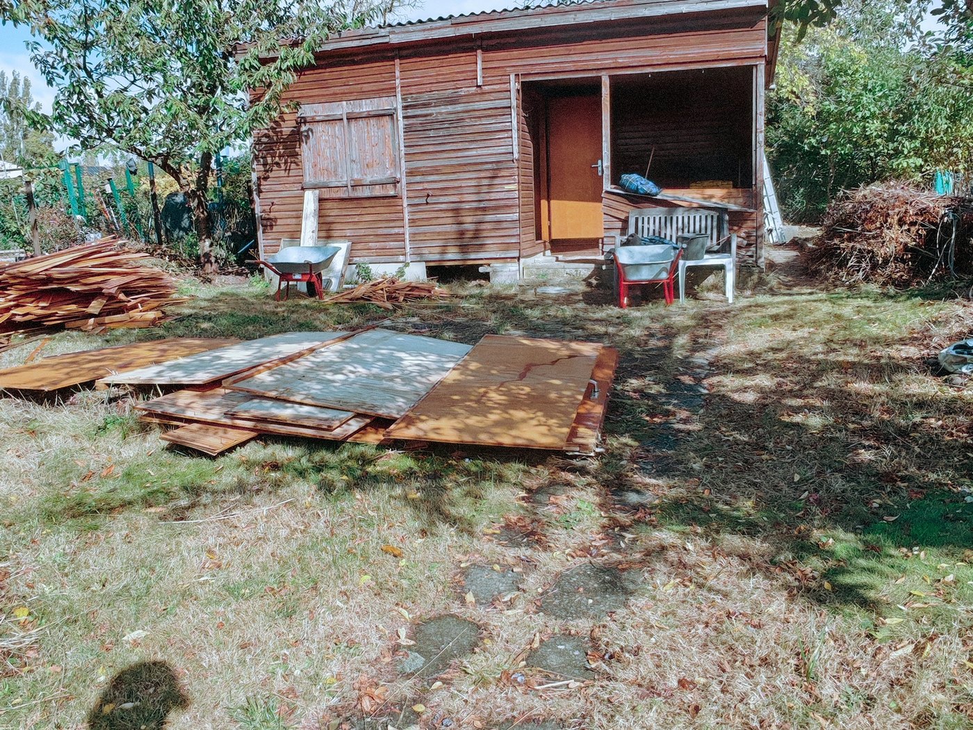 Holz-Gartenhaus in einem Steglitzer Garten, daneben liegen sortierte Bretter