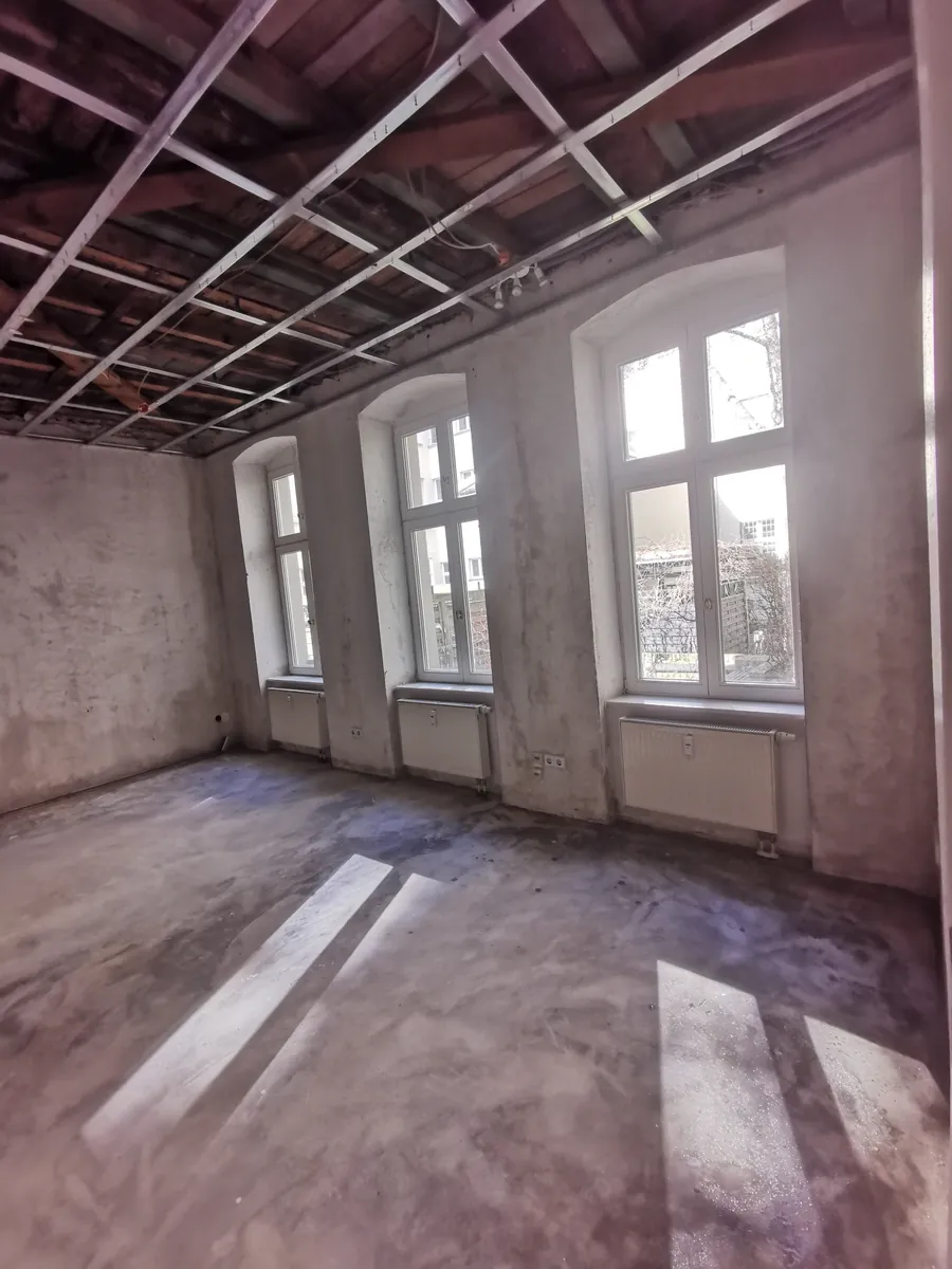 Entkernter Altbauraum in Berlin mit freigelegter Deckenkonstruktion und Tageslicht