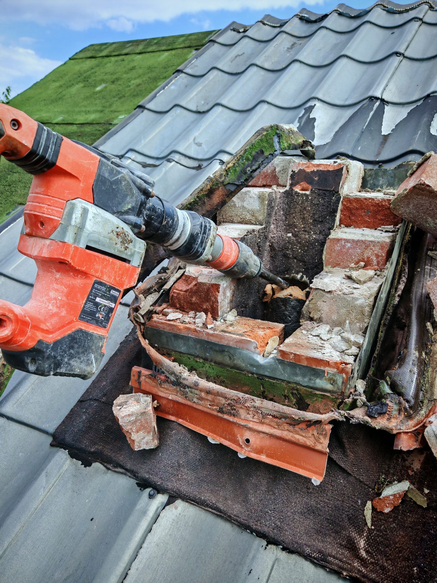 Schornsteinkopf wird mit dem Bohrhammer Ziegel für Ziegel abgetragen