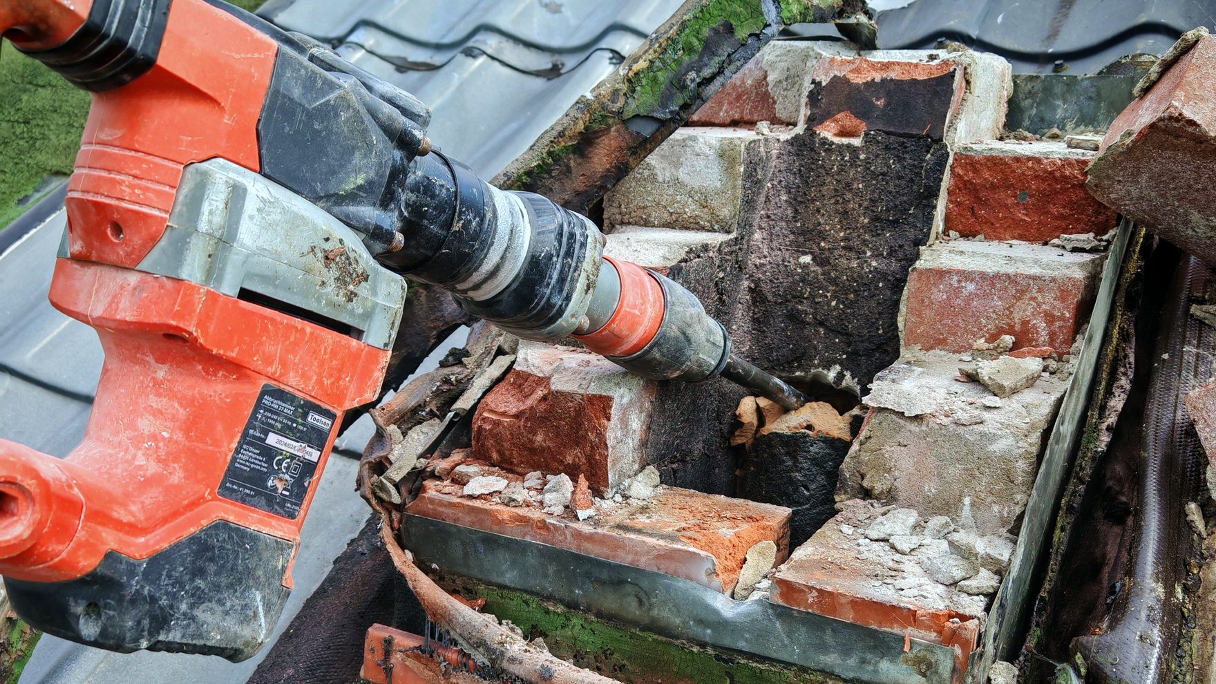 Schornsteinkopf wird auf dem Dach mit dem Abbruchhammer abgetragen