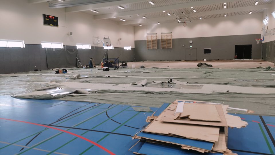 Sporthallenboden, dessen Belag in Bahnen aufgenommen wird