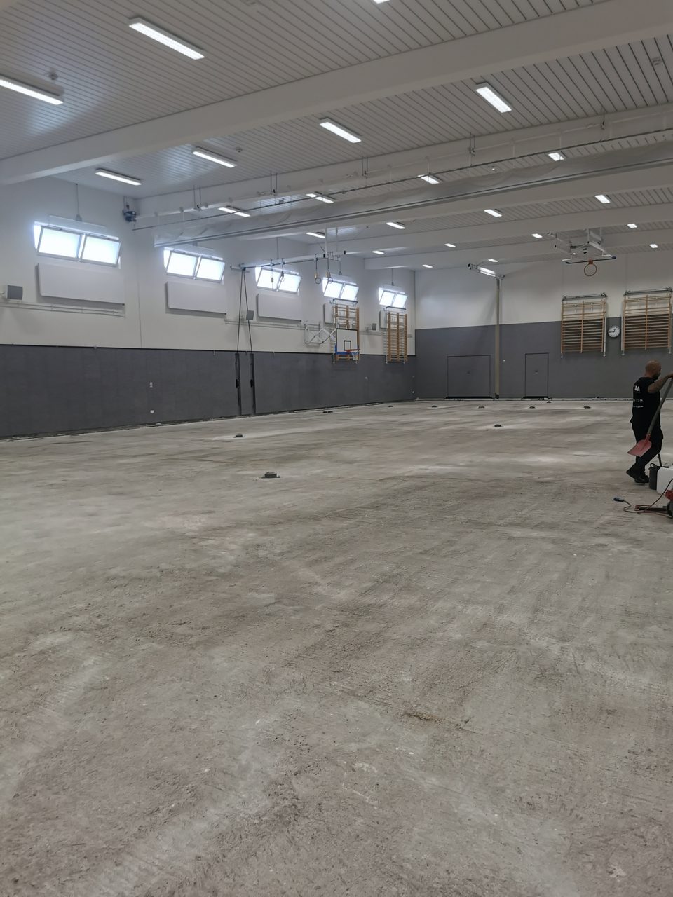 Leere Sporthalle mit besenreinem Betonboden nach dem Rückbau