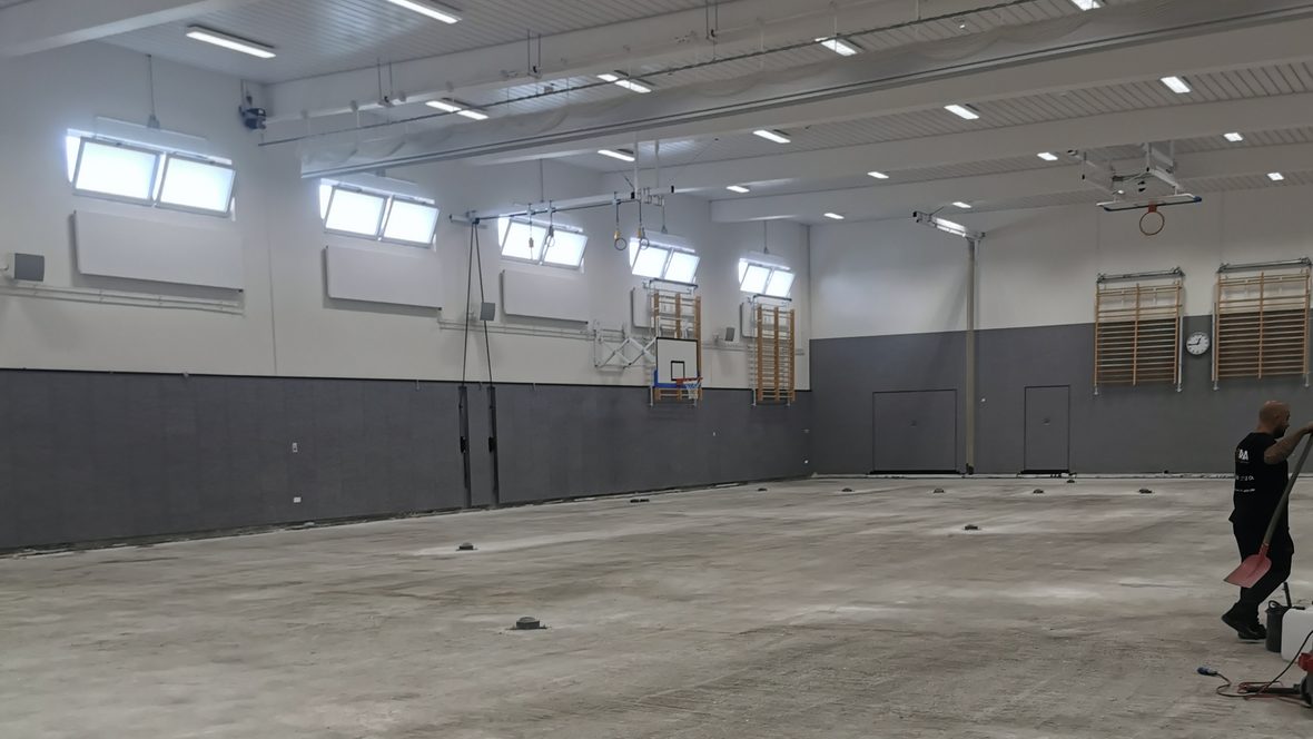 Leere Sporthalle, der Betonboden liegt frei und ist besenrein