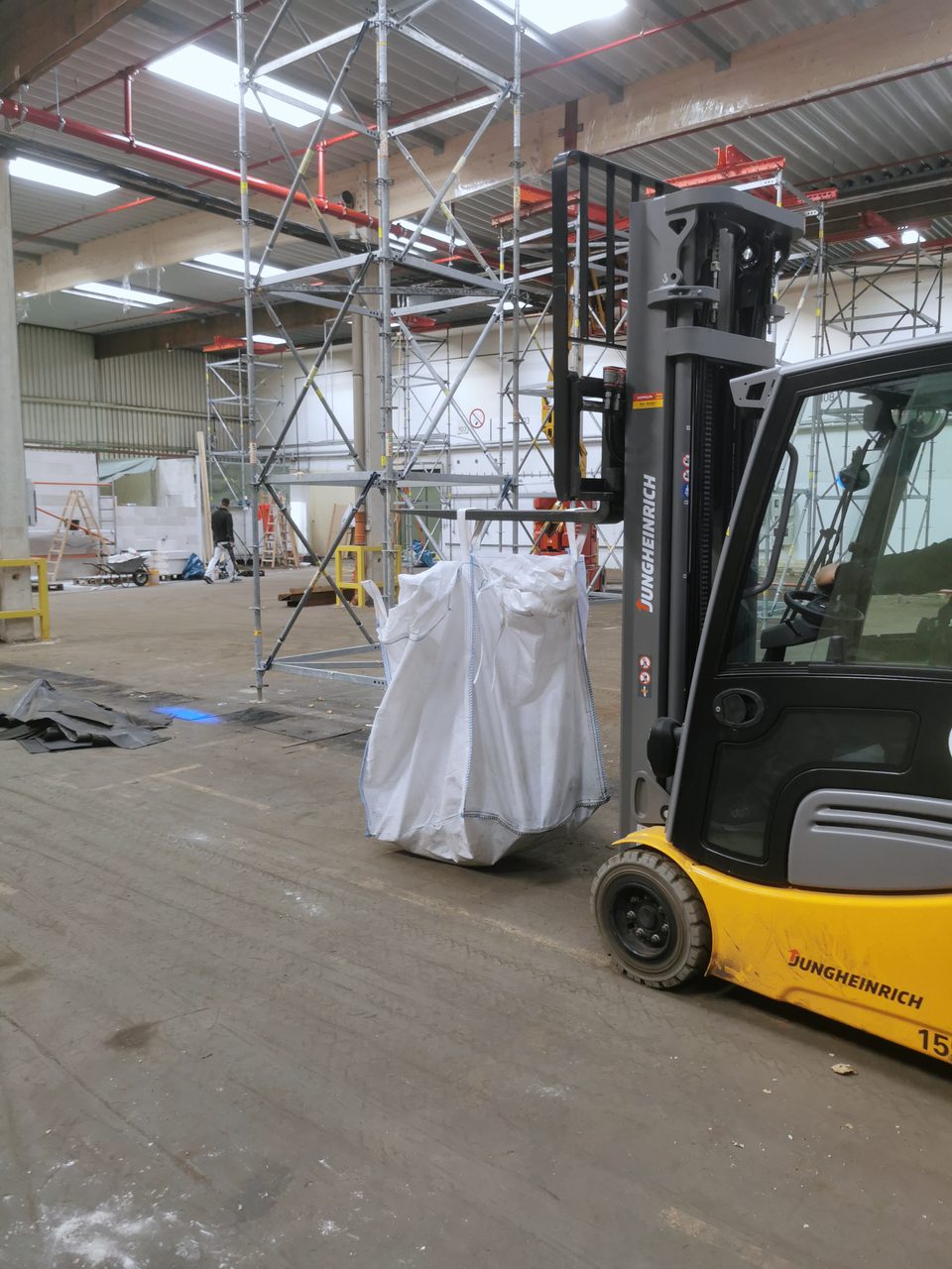 Stapler trägt einen gefüllten Big Bag durch dieselbe Halle