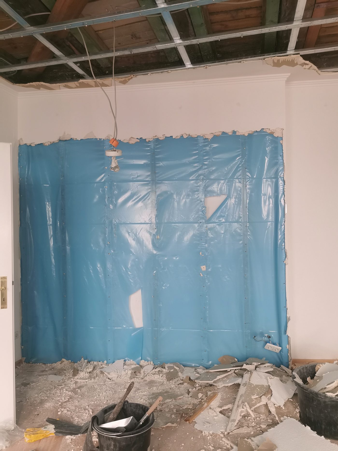 Wohnungstür mit blauer Folie eingehaust, davor eine Staubschutzwand