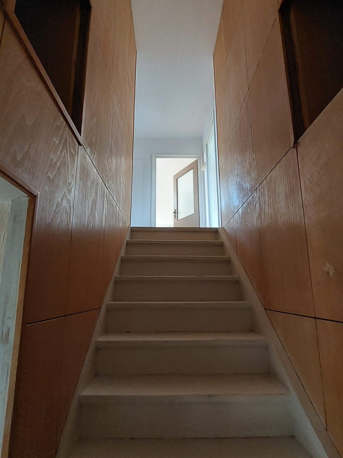 Treppenaufgang mit dunkler Holzvertäfelung und Teppichstufen vor der Entkernung