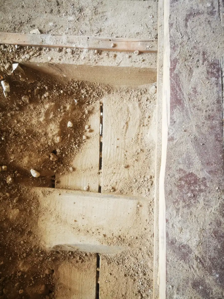 Geöffnete Altbauwand mit sichtbarer Schüttung zwischen den Deckenbalken