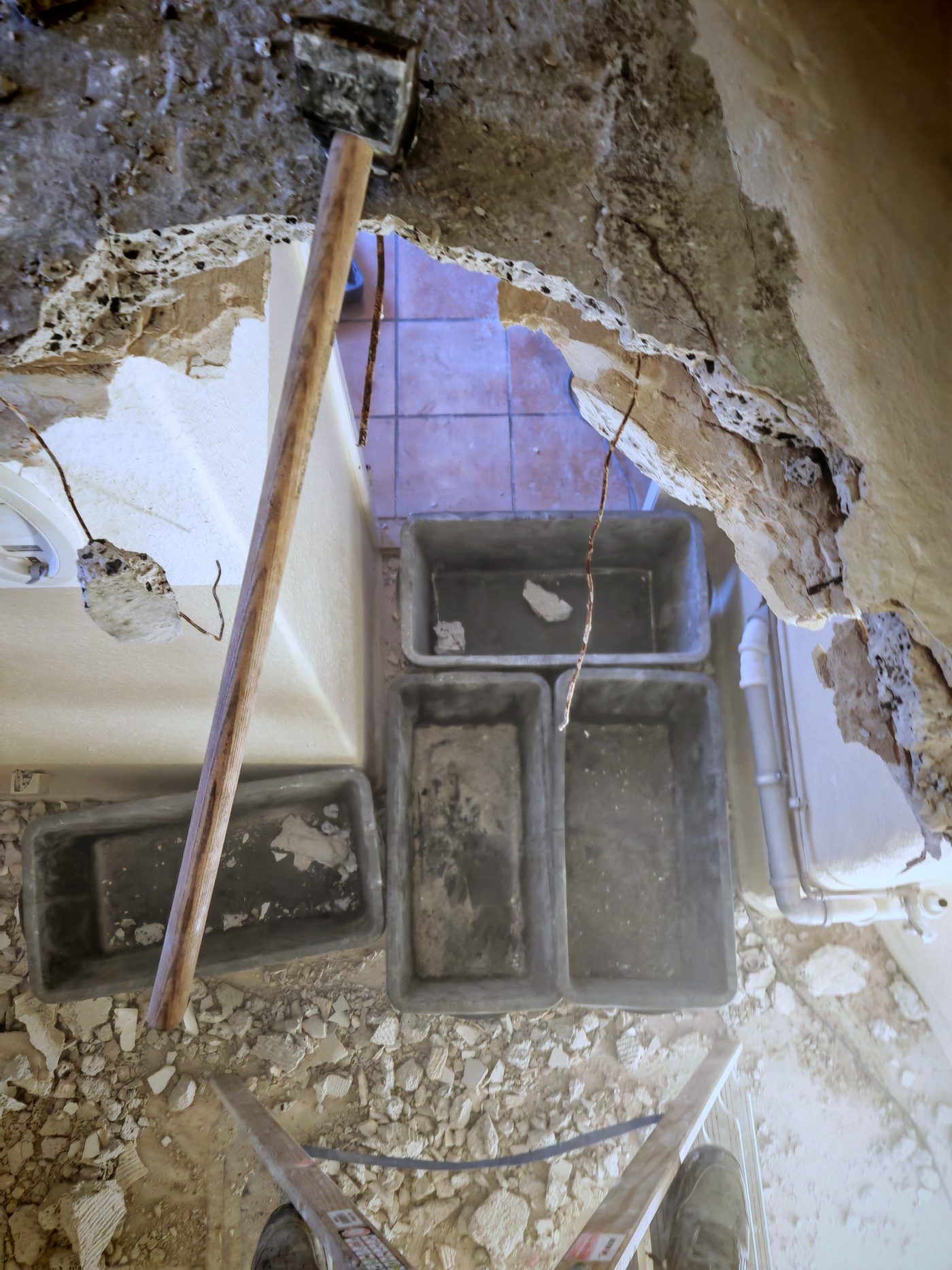 Geöffneter Wanddurchbruch im Altbau-Mauerwerk, Vorschlaghammer im Loch, Mörtelwannen darunter