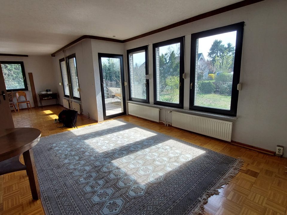 Bewohntes Wohnzimmer mit Dielenboden, Teppich und Fensterfront